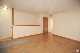 Spacious interior room featuring wood-finish flooring, light-toned wall paint, and a textured ceiling