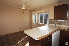 Kitchen area featuring dark wood-finish cabinetry, light-toned countertops, and a stone-look tile backsplash