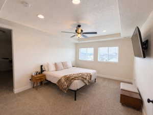 Primary bedroom featuring carpet, a tray ceiling with recessed lighting and a ceiling fan