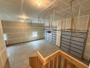 Spacious garage with exposed drywall, concrete flooring, two overhead garage doors, light fixtures, and windows providing natural light