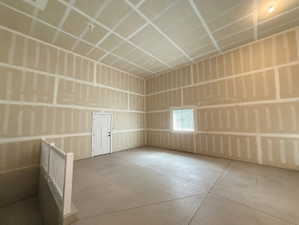 Unfinished interior space featuring high ceilings, exposed drywall, and concrete flooring