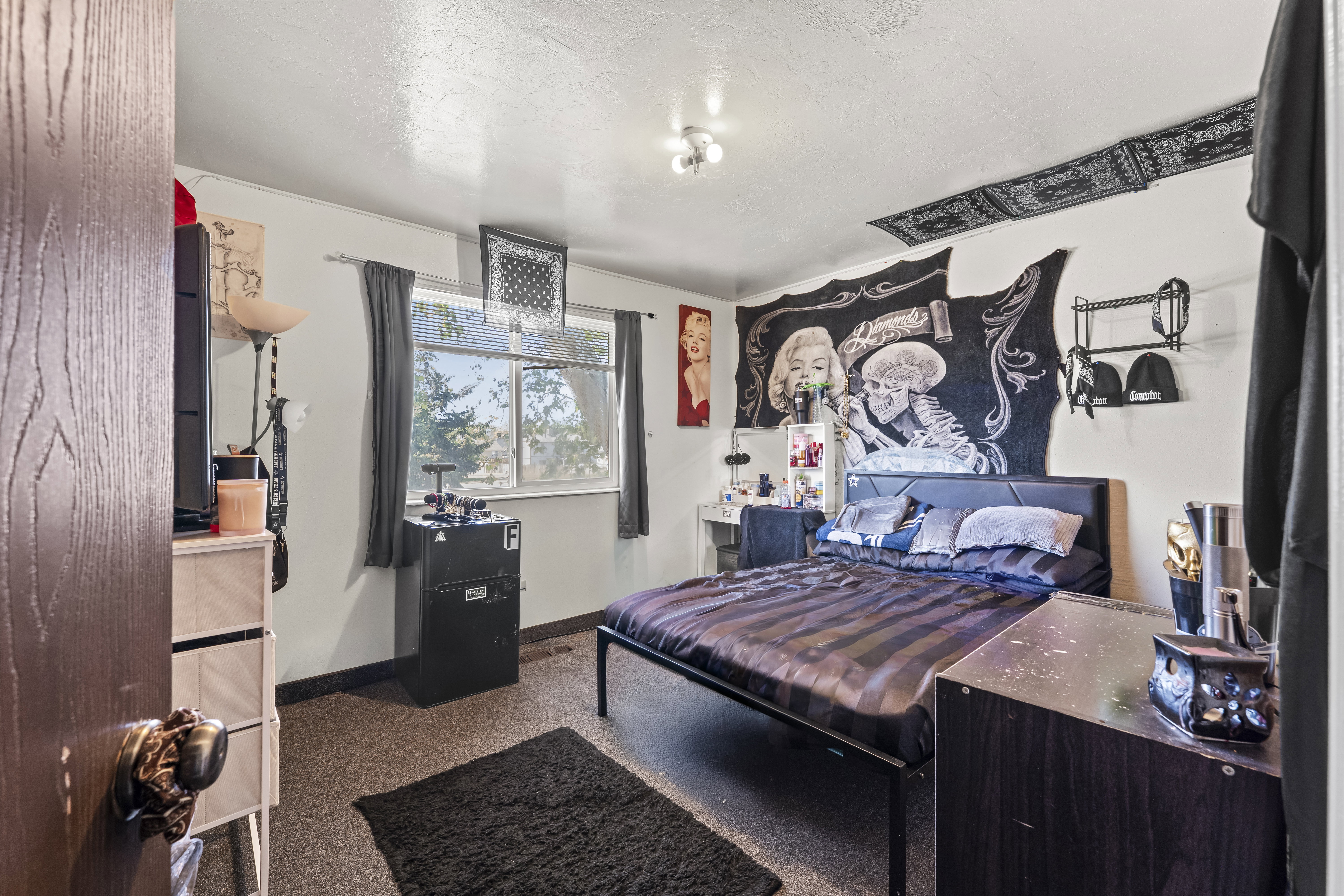 Bedroom featuring a large window, textured walls, and a ceiling-mounted light fixture