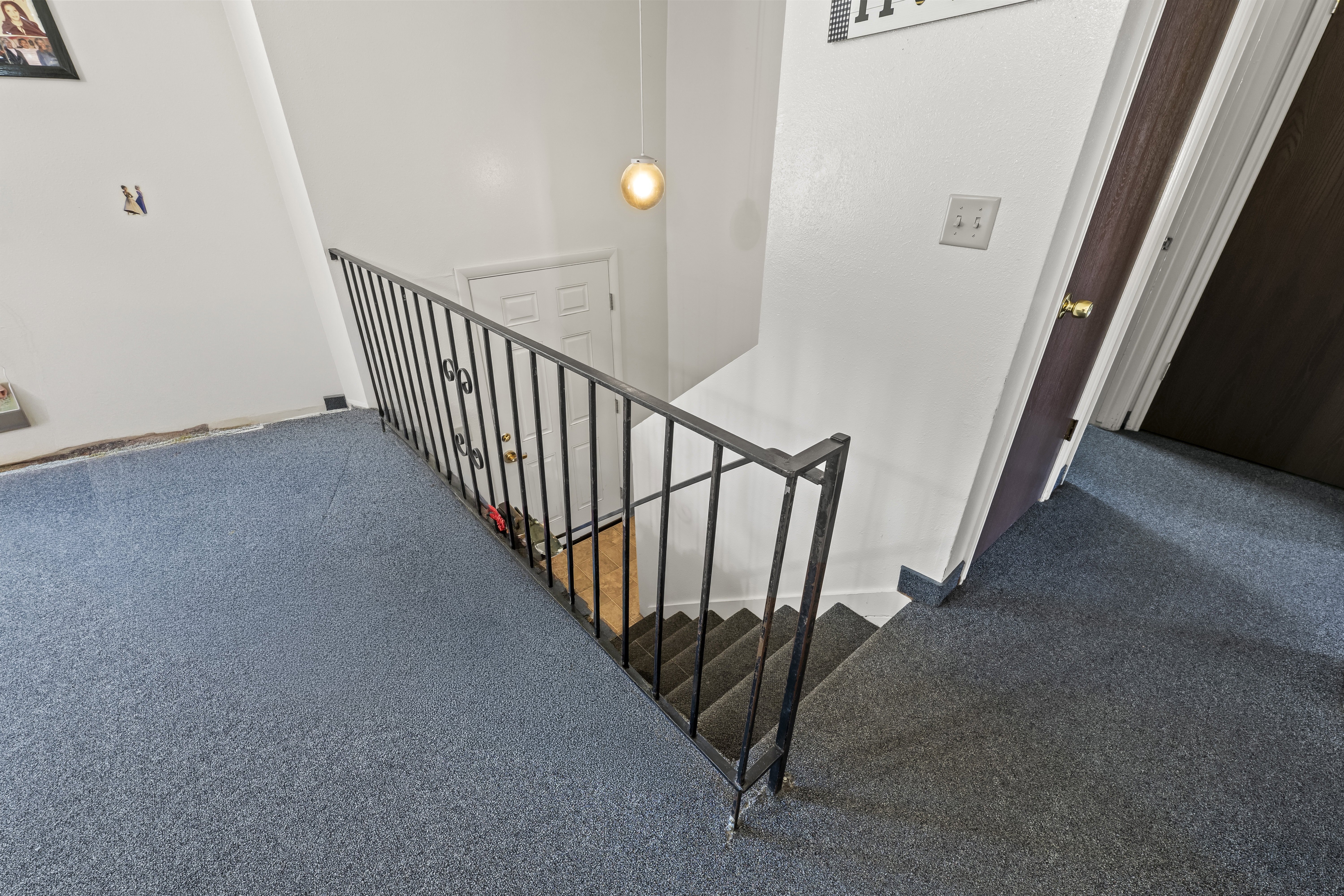 Stairwell featuring metal railings and a pendant light fixture