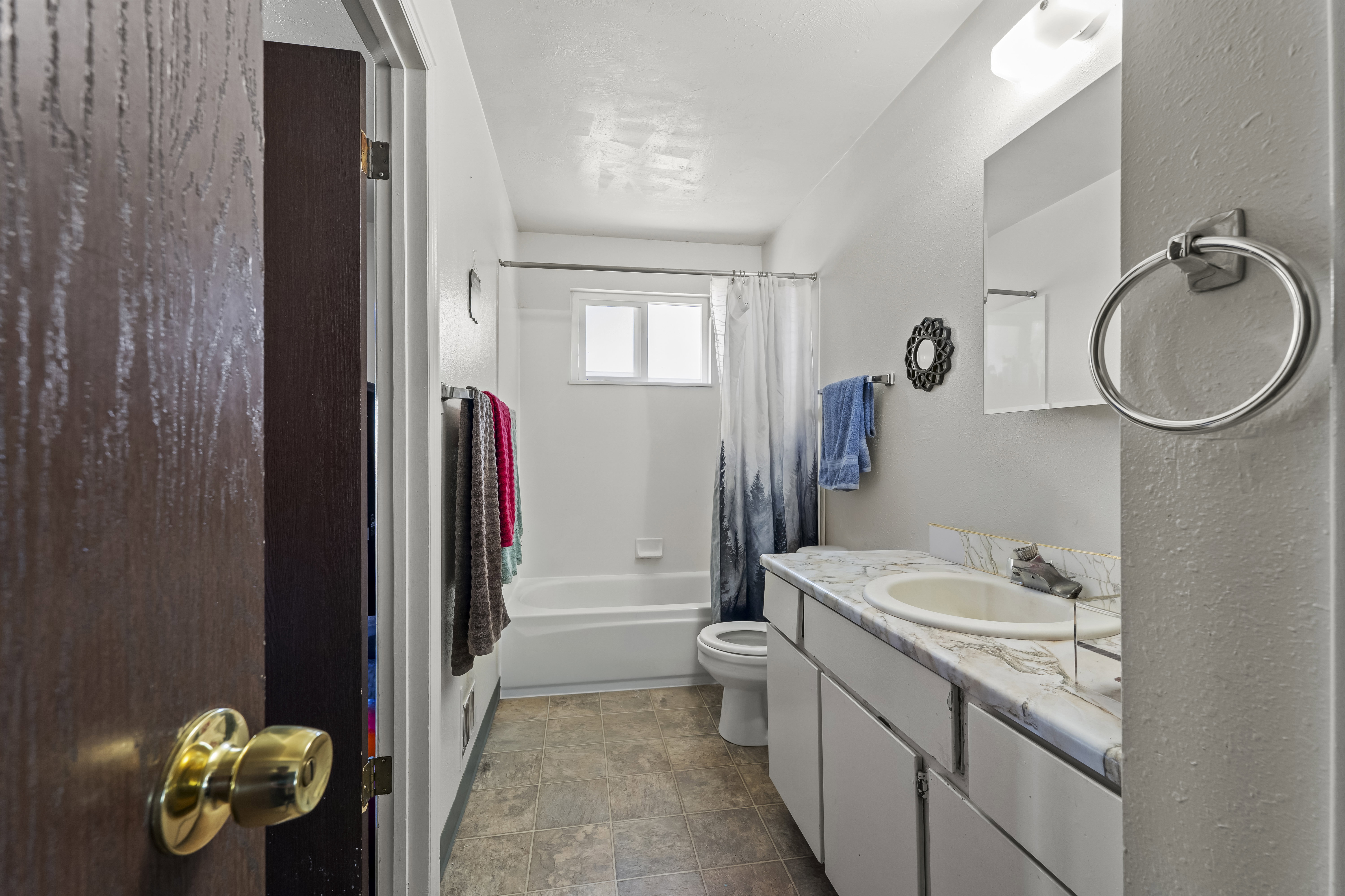 Bathroom featuring a white vanity with an integrated sink, patterned countertop, and mirrored medicine cabinet