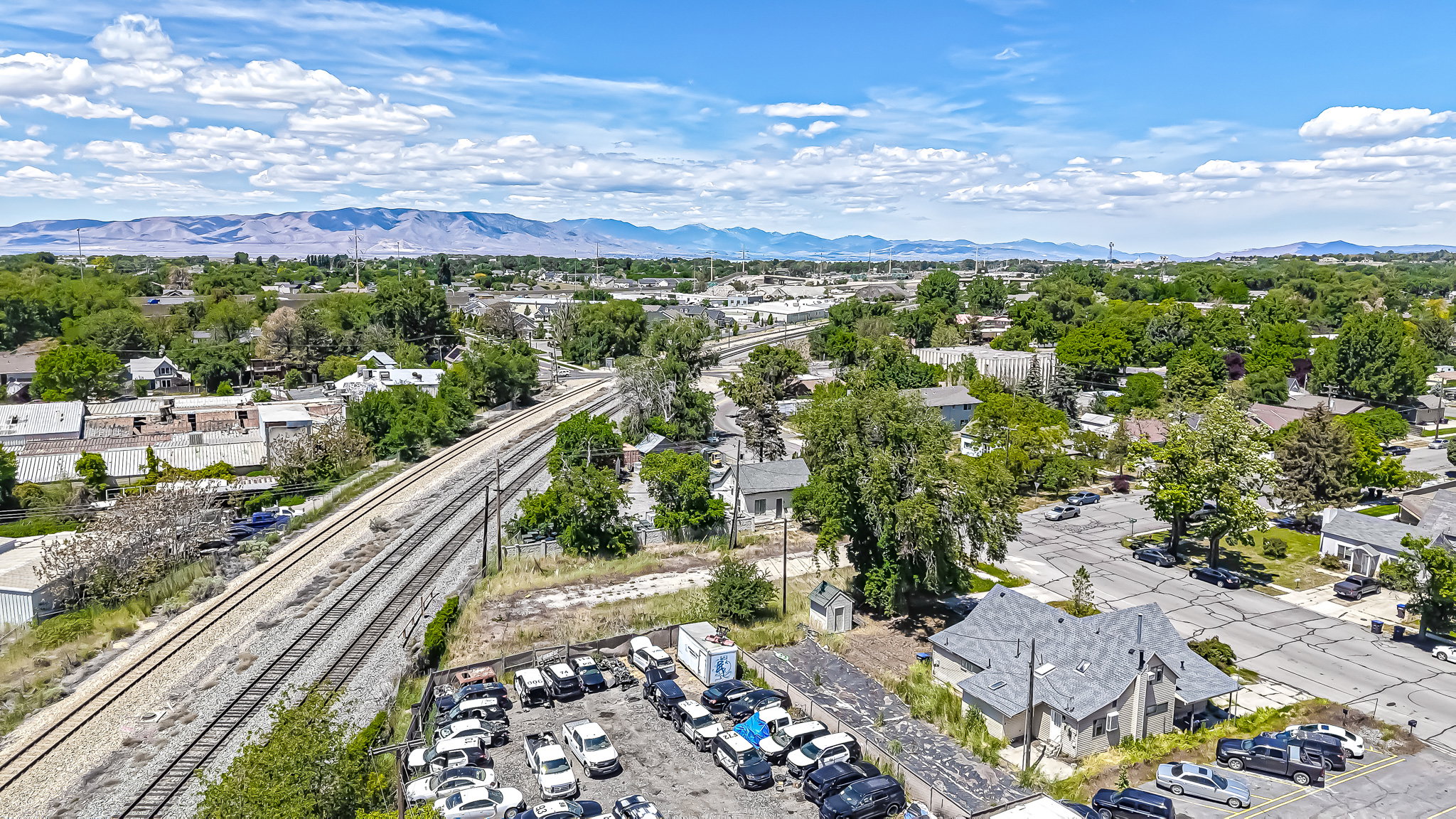 Aerial perspective highlighting the surrounding neighborhood with mature trees and a prominent mountain range in the distance