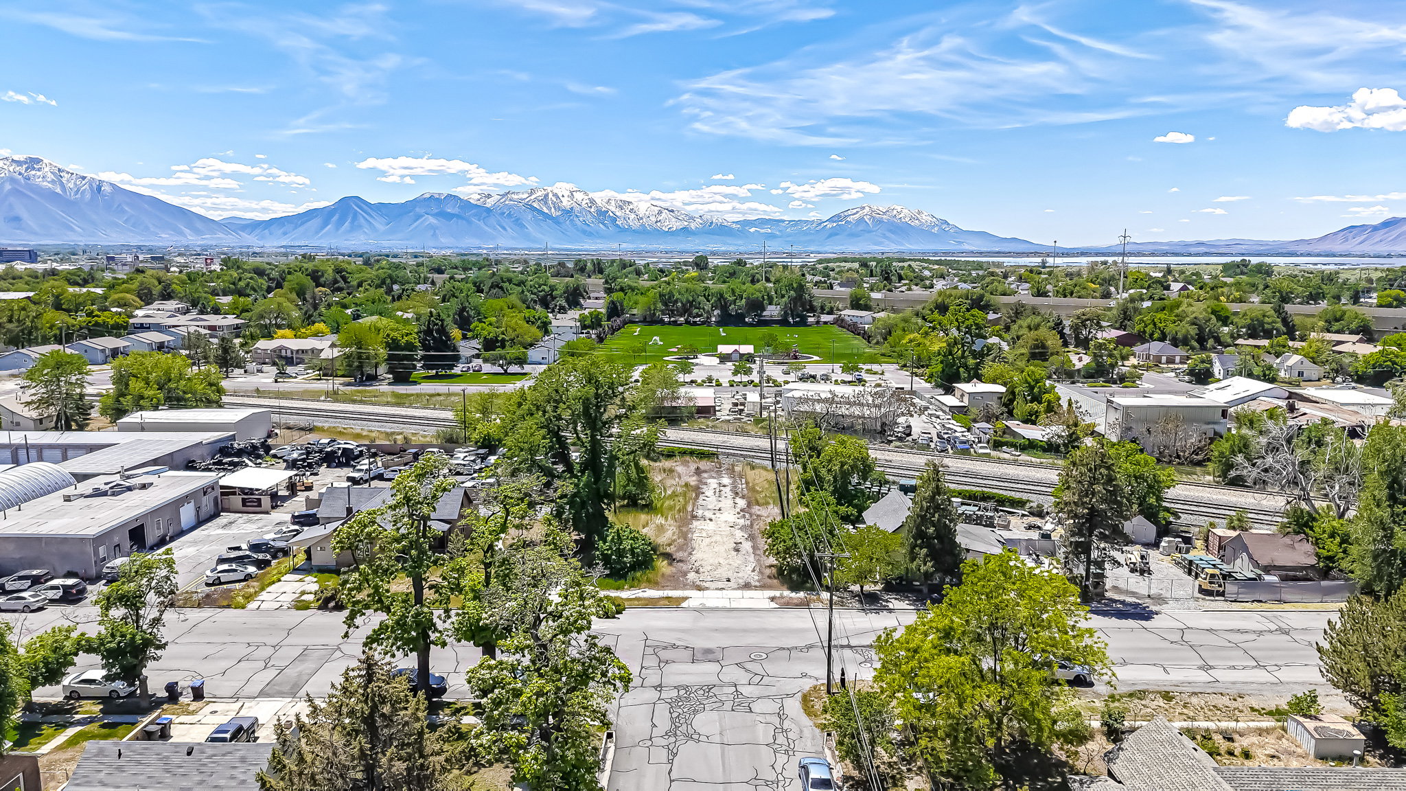 Expansive aerial perspective showcasing a mountainous backdrop, a distant body of water, and surrounding greenery