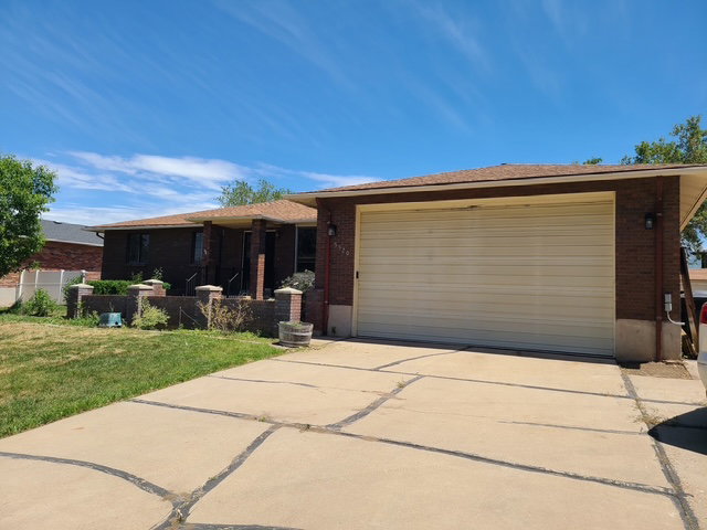 Brick exterior residence with a two-car garage, concrete driveway, and front landscaping elements