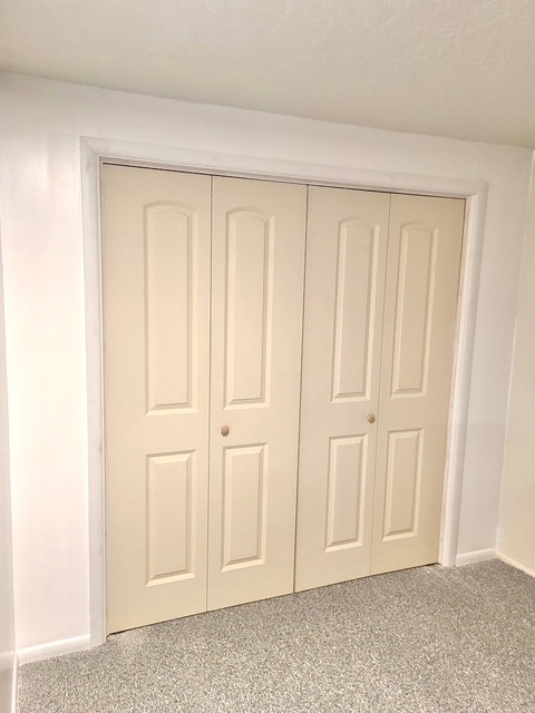 Cream-colored bi-fold closet doors with panel detailing and light-toned knobs