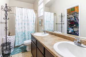 Bathroom featuring a double vanity with integrated sinks, a built-in mirror, an enclosed shower with a shower curtain, and a window providing natural light