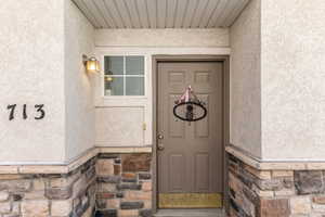 Entryway featuring textured stucco siding and a stone veneer foundation