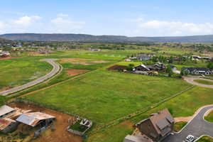 Expansive green fields with distant mountains and established residential structures
