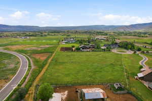 Expansive green acreage featuring a winding paved road and mountain backdrop