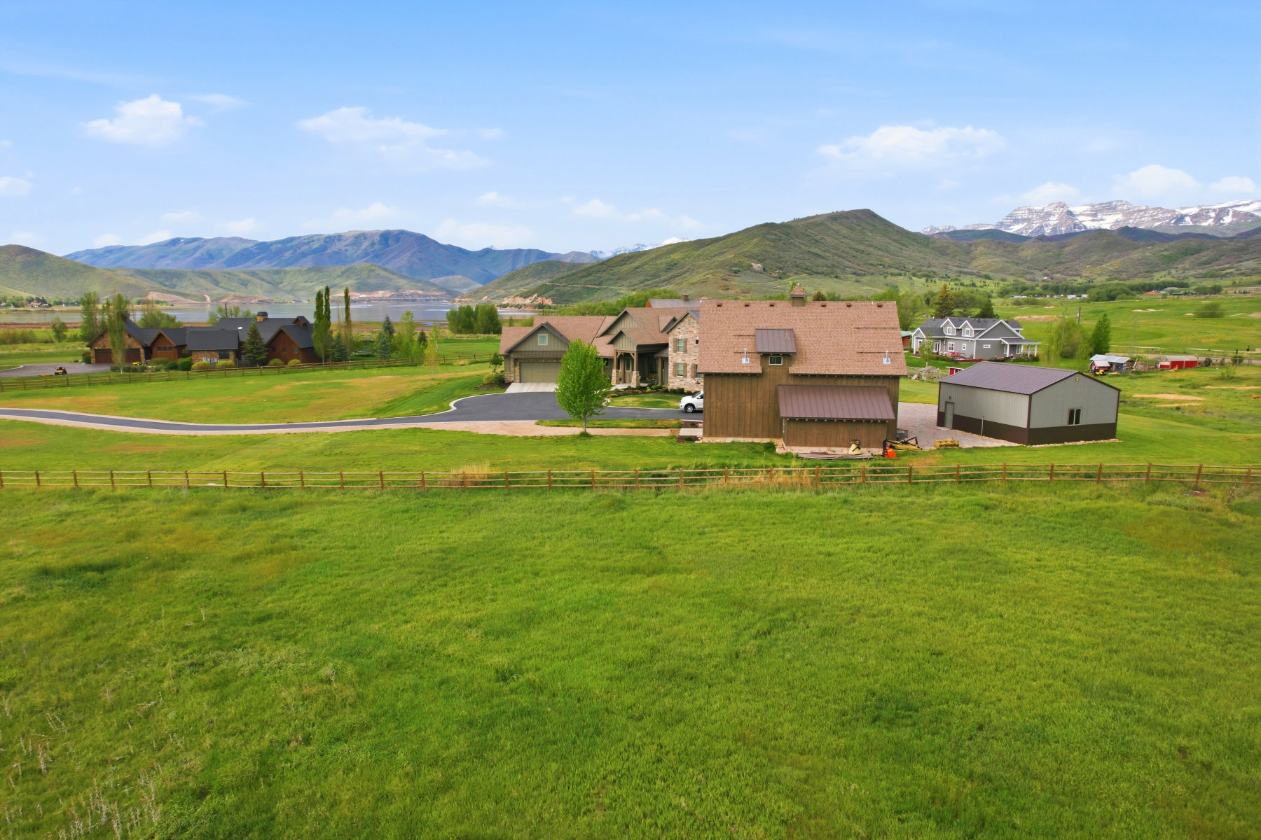 Expansive green acreage featuring a primary residence with an attached garage, a separate barn-style structure, and a large metal outbuilding