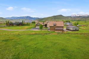 Expansive green acreage featuring a primary residence with an attached garage, a separate barn-style structure, and a large metal outbuilding