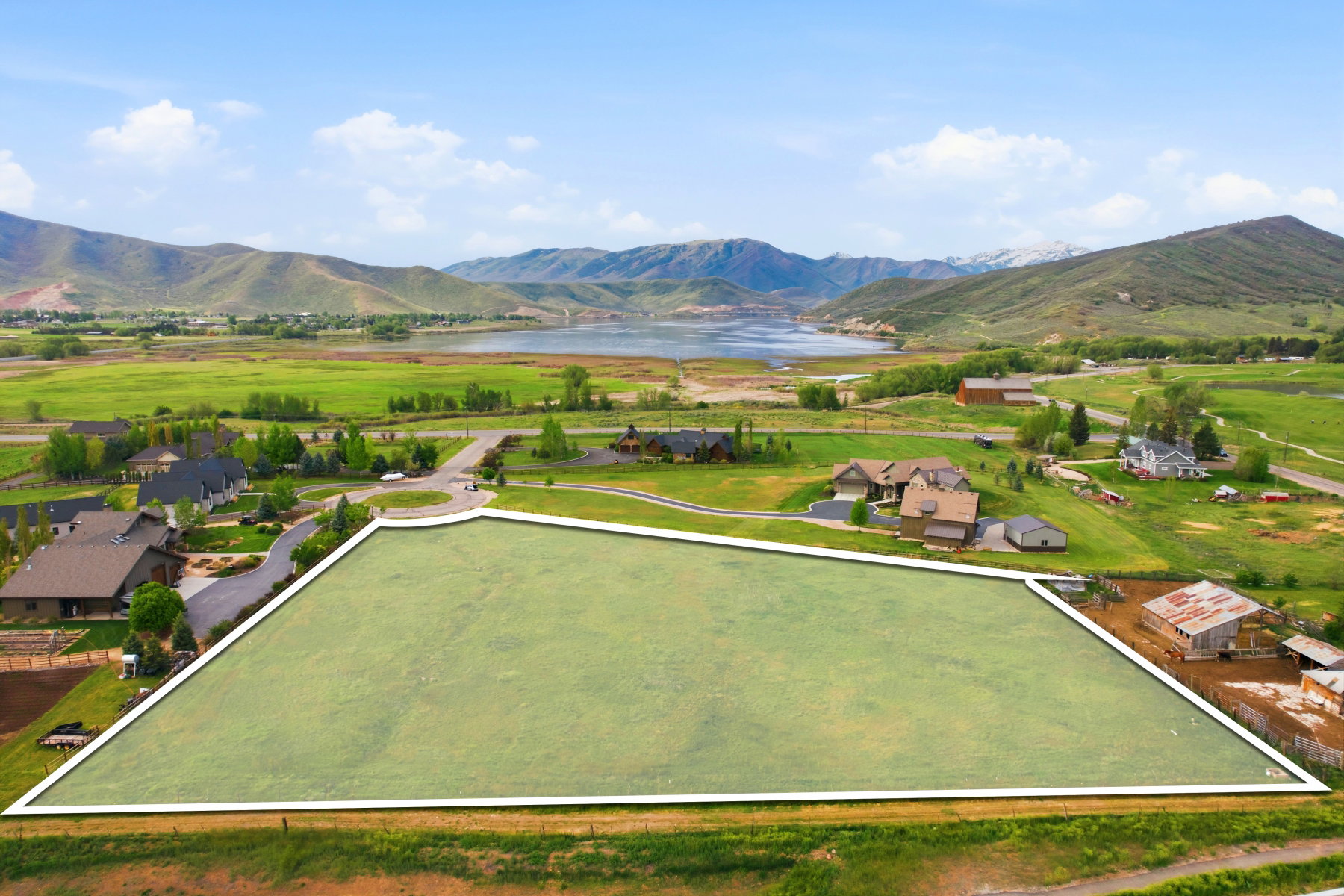 Expansive green parcel featuring mountain and lake scenery, surrounded by other residences and natural landscapes