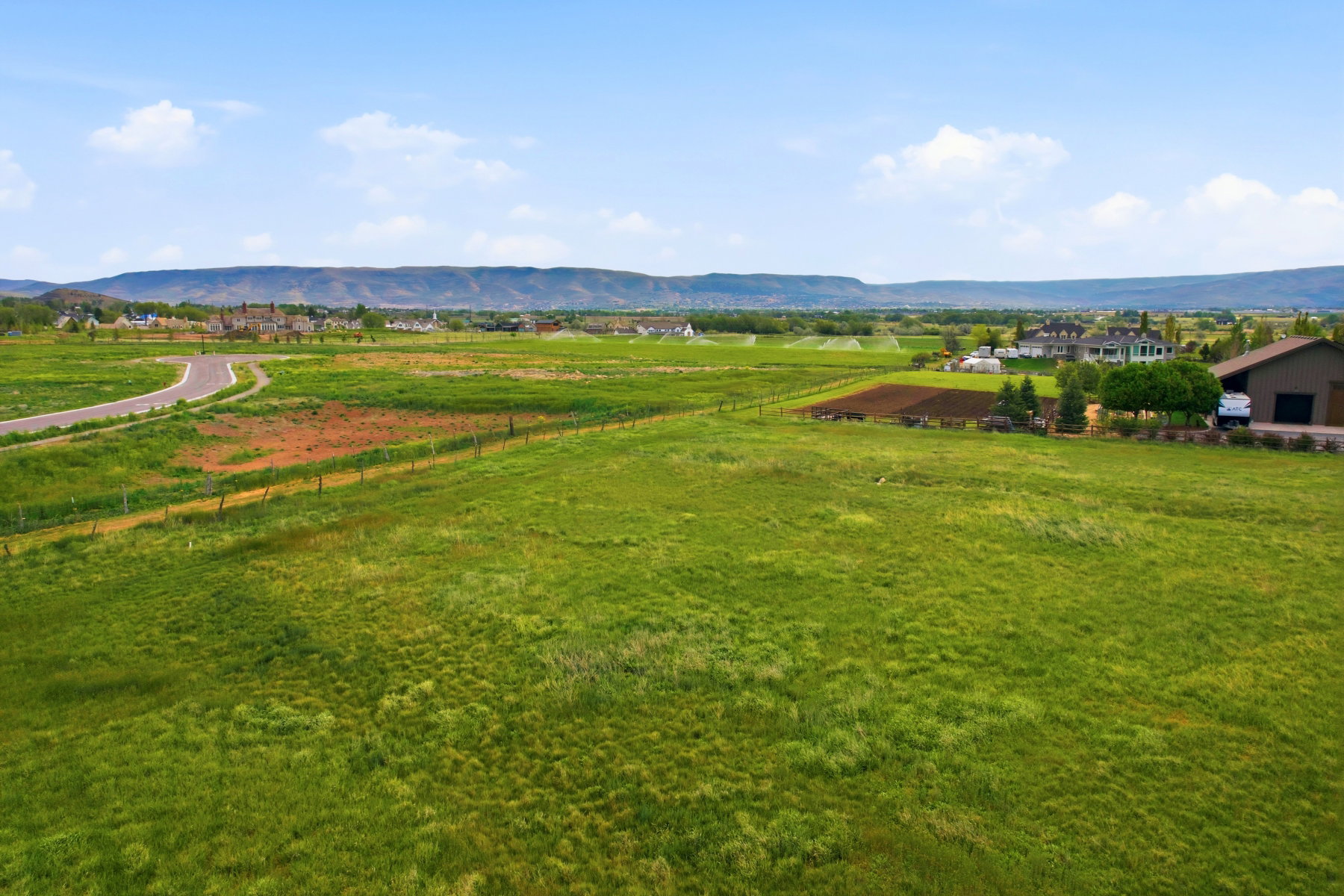 Expansive green field with distant mountain range backdrop