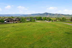 Expansive green pasture with a split-rail fence and a winding road