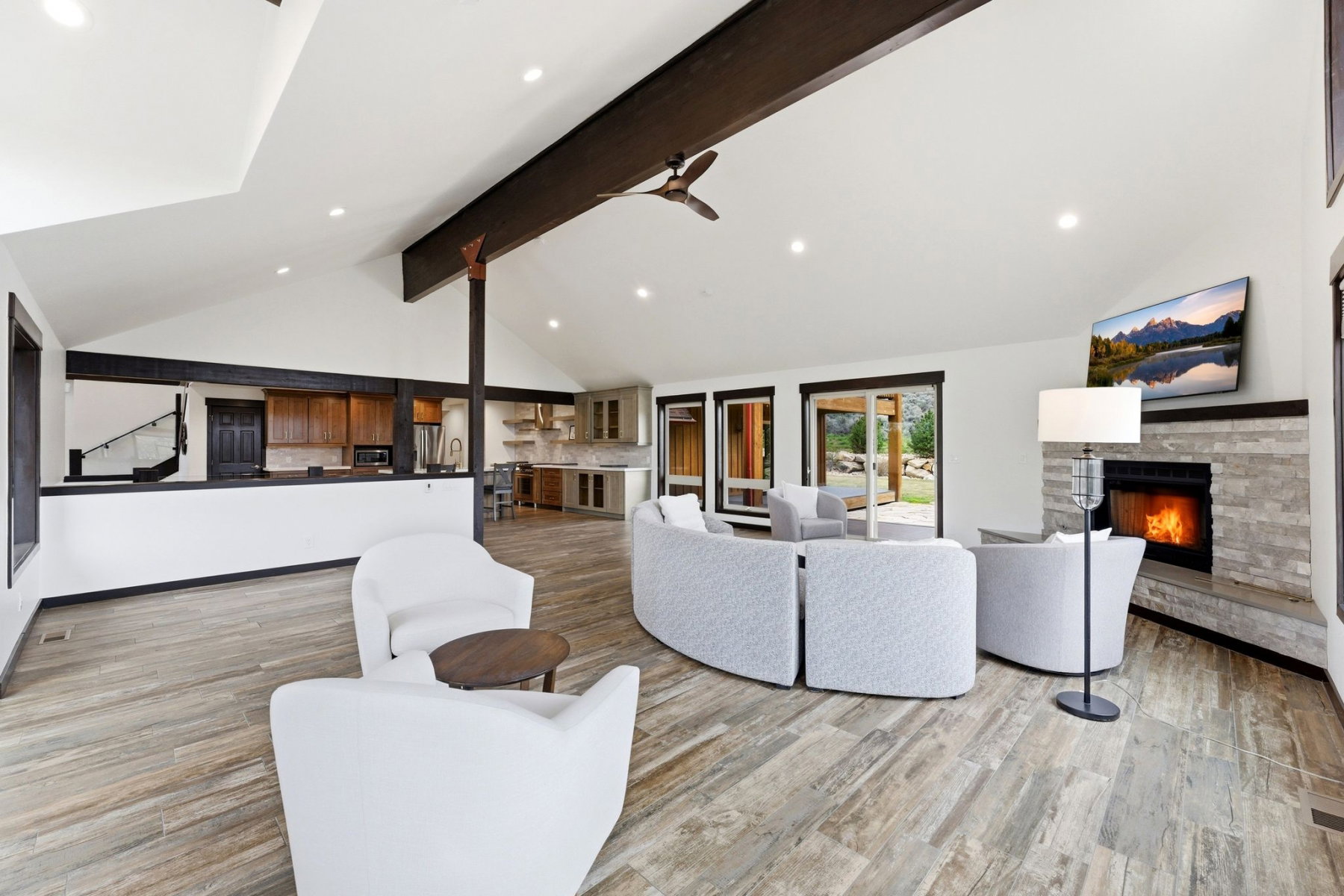 Spacious living area featuring vaulted ceilings with exposed beams, recessed lighting, and wood-finish flooring