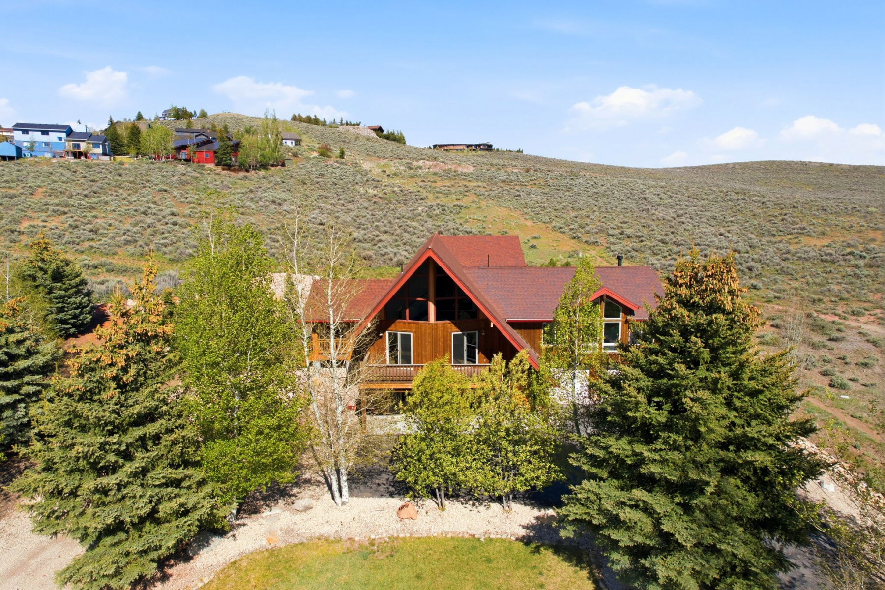 Wood-sided residence featuring a red shingled roof, A-frame architectural elements, and multiple balconies