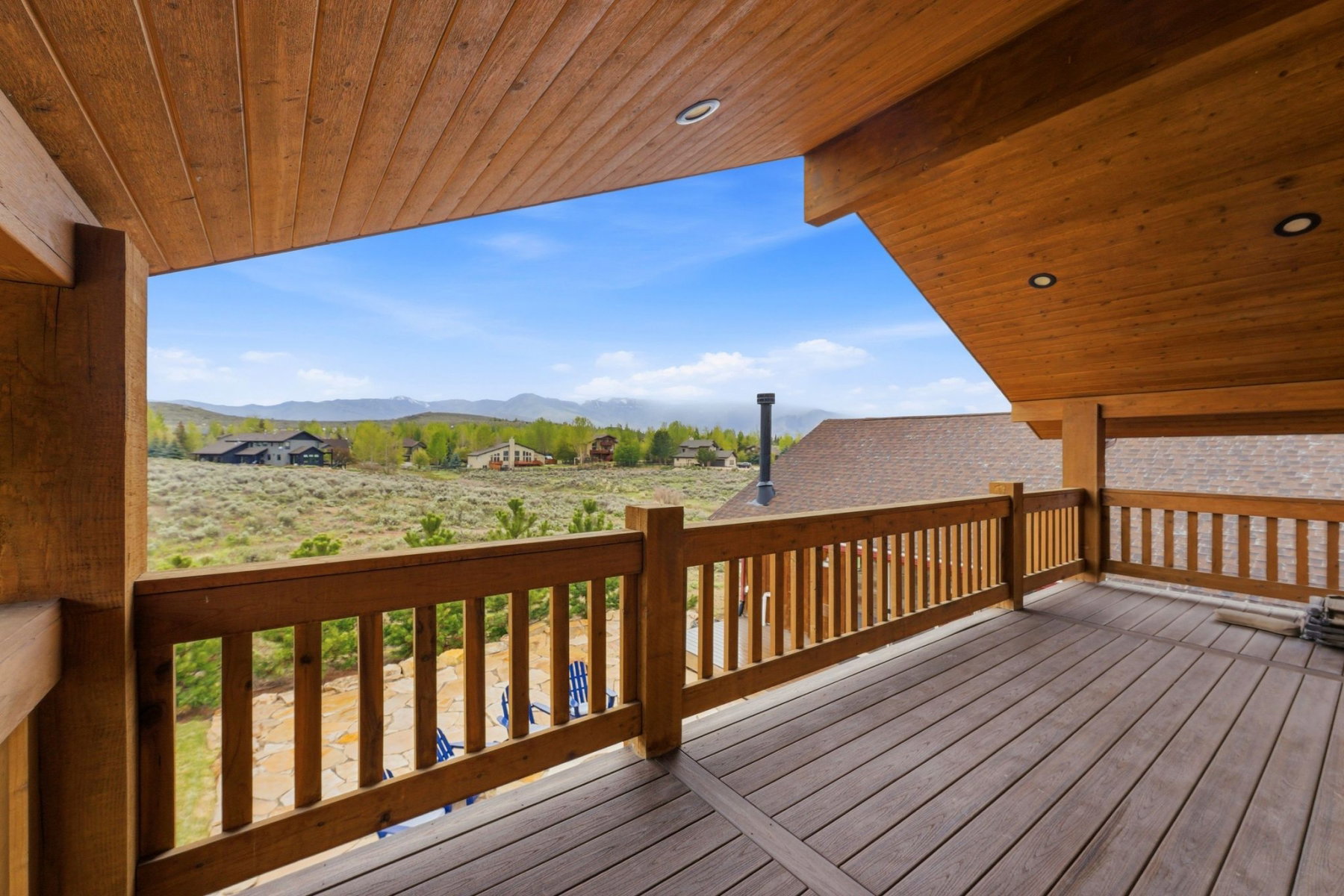 Spacious wooden deck with slatted railings and a natural wood plank ceiling featuring recessed lighting