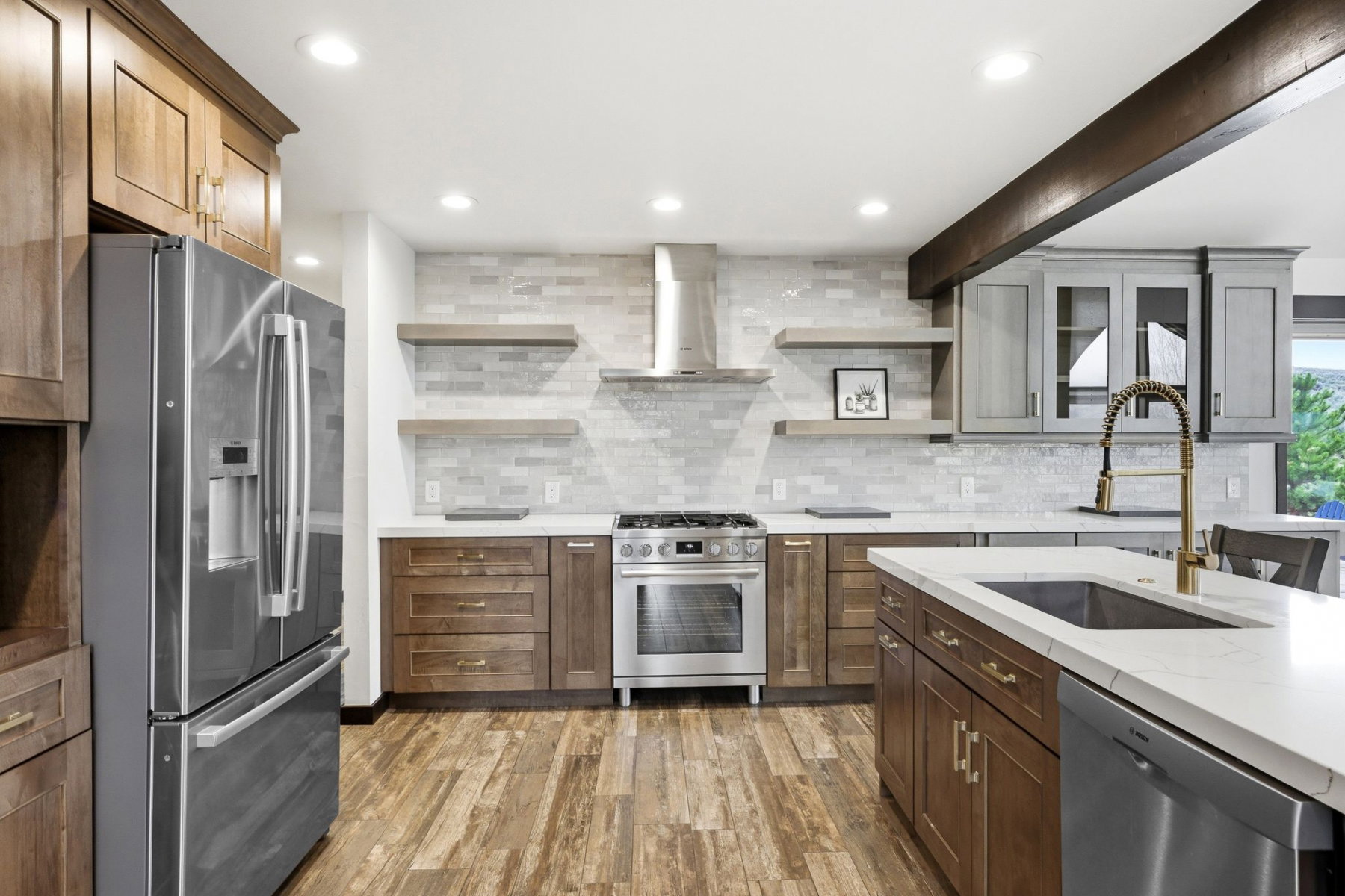 Modern kitchen featuring stainless steel appliances, wood-finish flooring, a contemporary range hood, white quartz countertops, and a subway tile backsplash