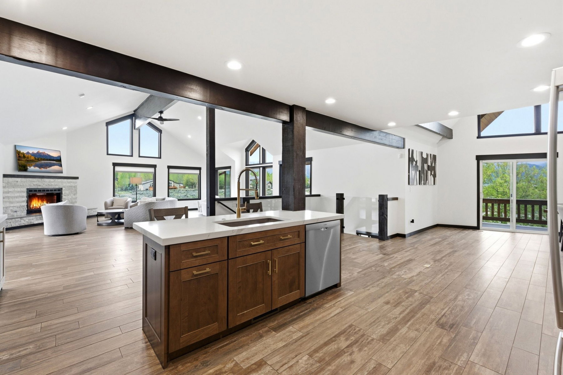 Kitchen island featuring wood cabinetry, white countertop, and an undermount sink with a gooseneck faucet