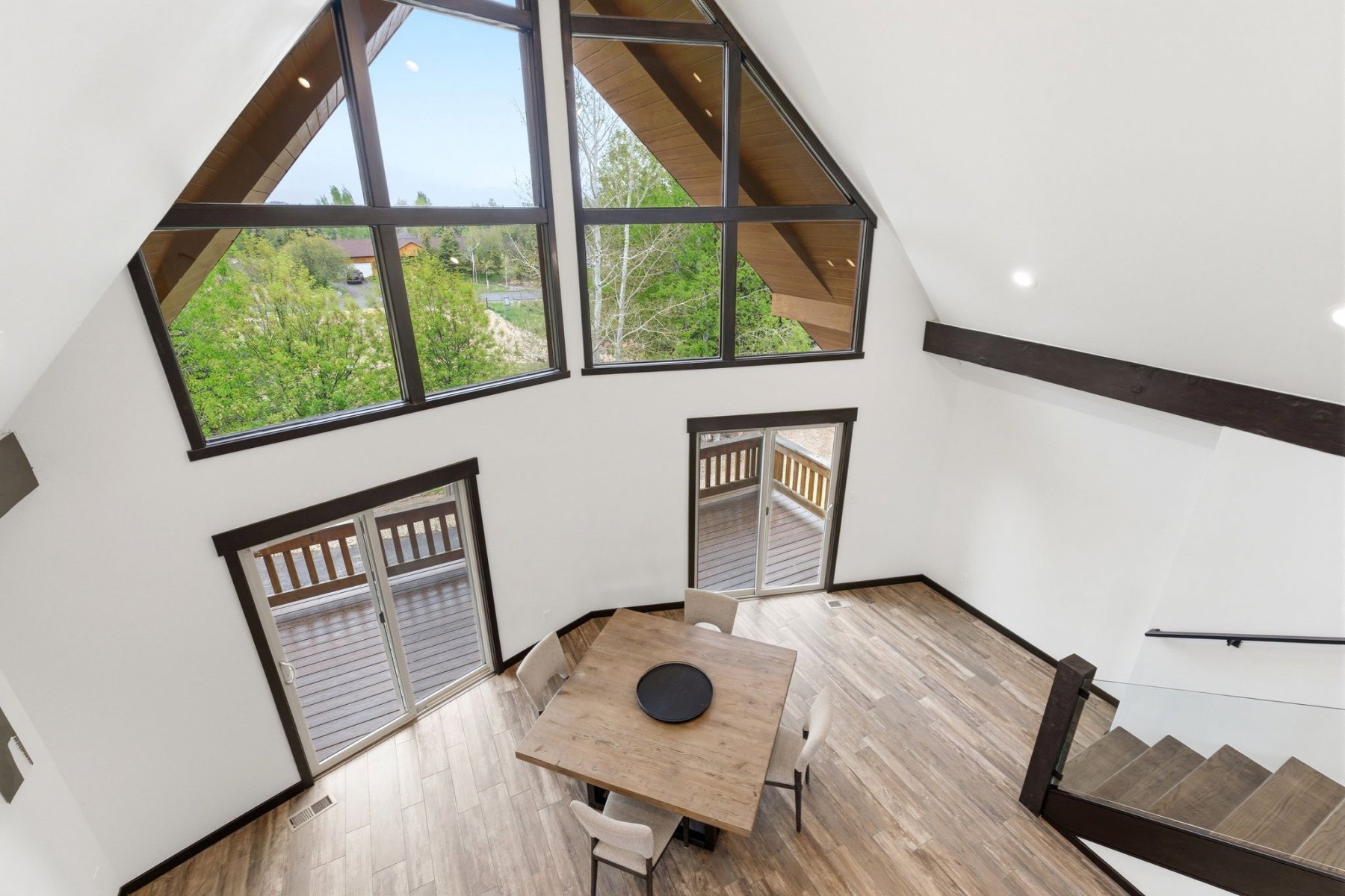 Vaulted ceilings featuring exposed dark wood beams and expansive windows