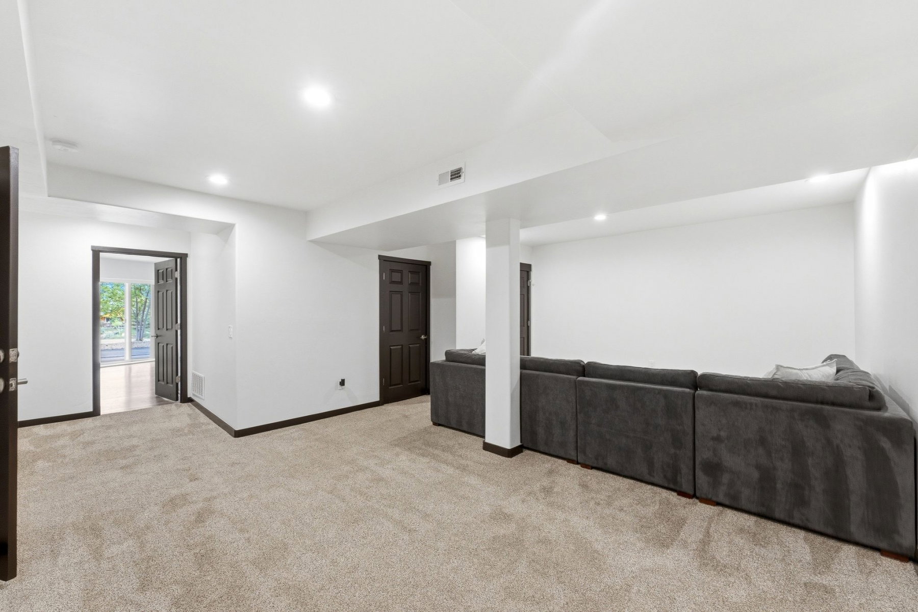 Spacious room featuring light-colored carpeting, recessed lighting, and white walls with dark trim