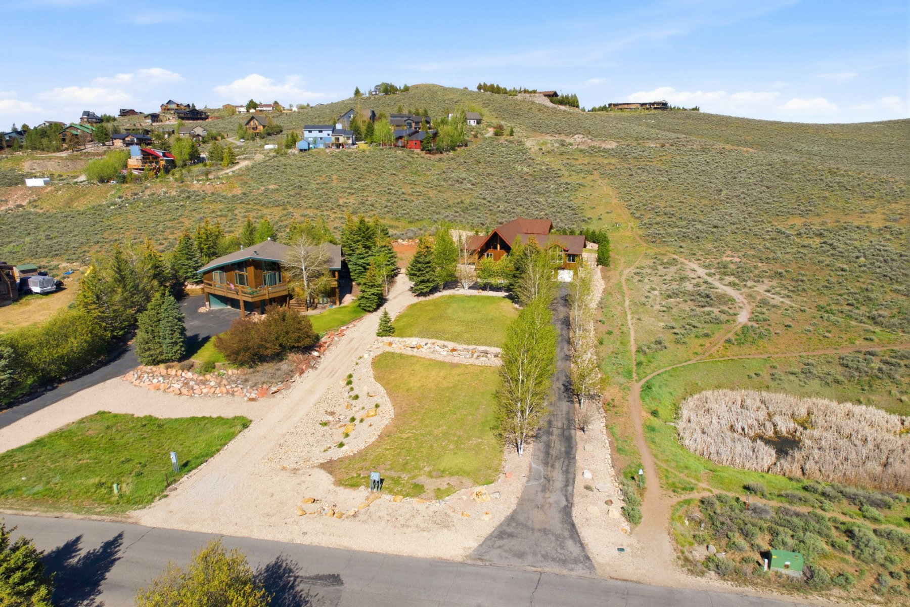 Expansive lot featuring a paved driveway and gravel-finished parking areas