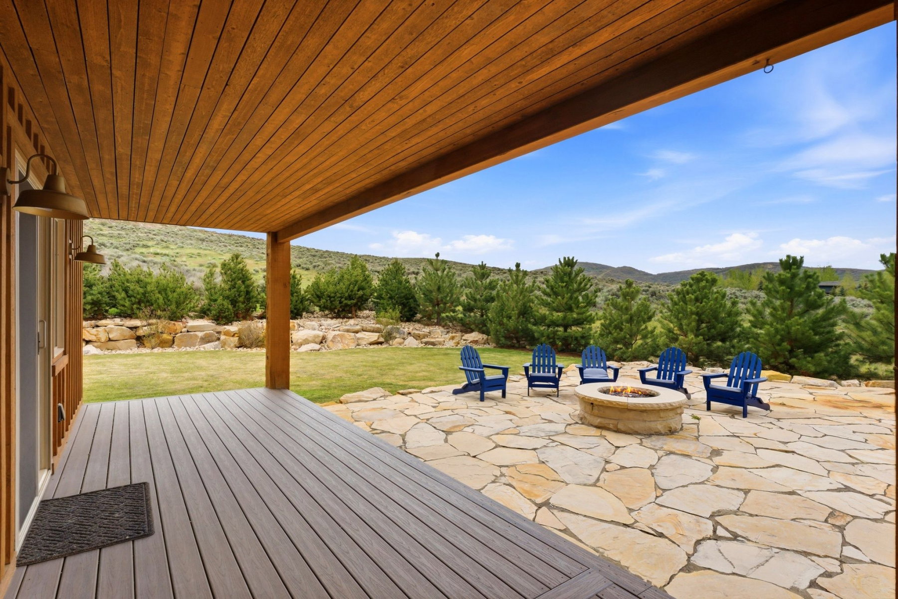 Expansive outdoor living area featuring a covered deck, flagstone patio, and a built-in stone fire pit