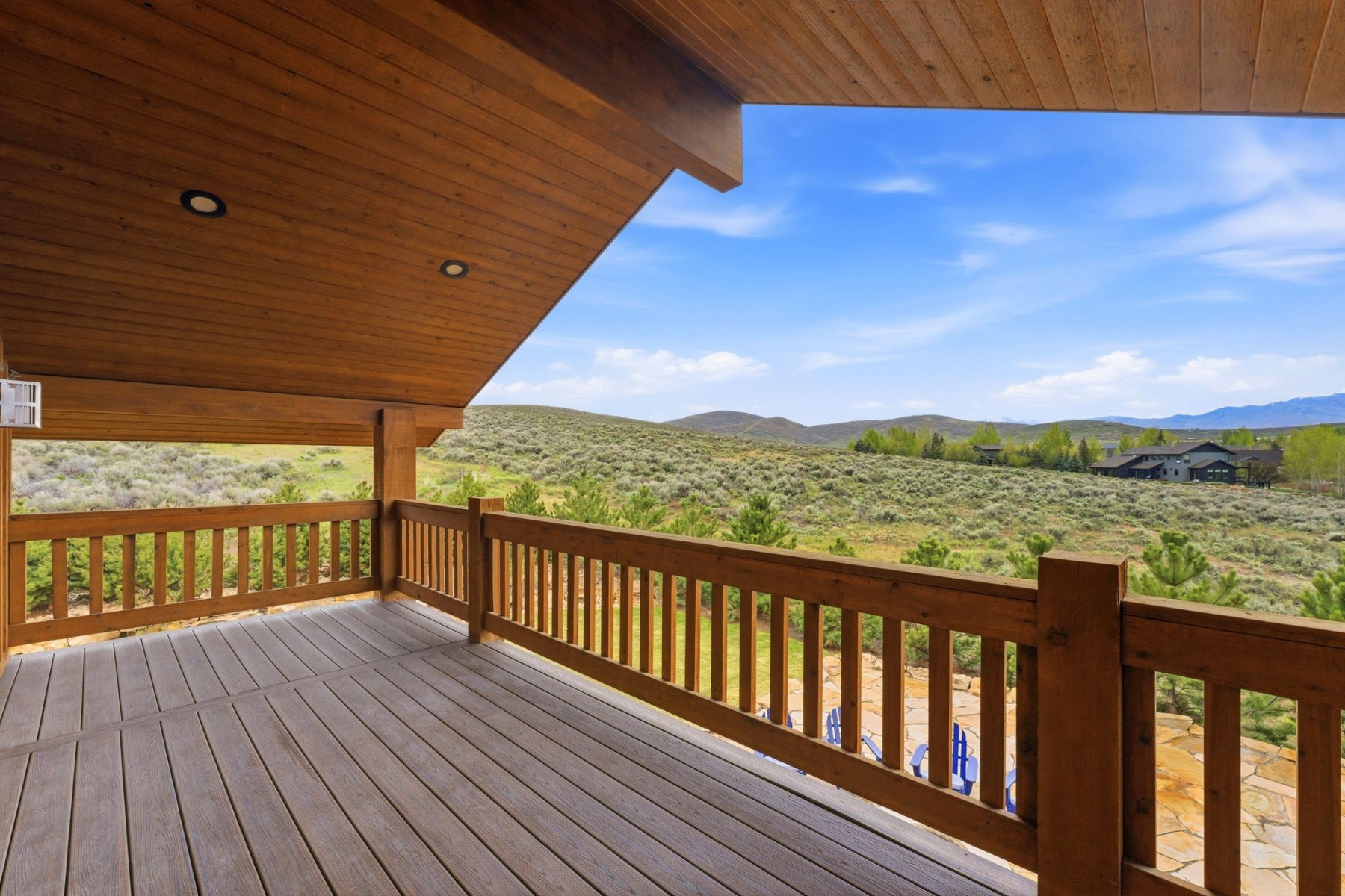 Expansive covered deck featuring wood-finish flooring and a wood-slat railing
