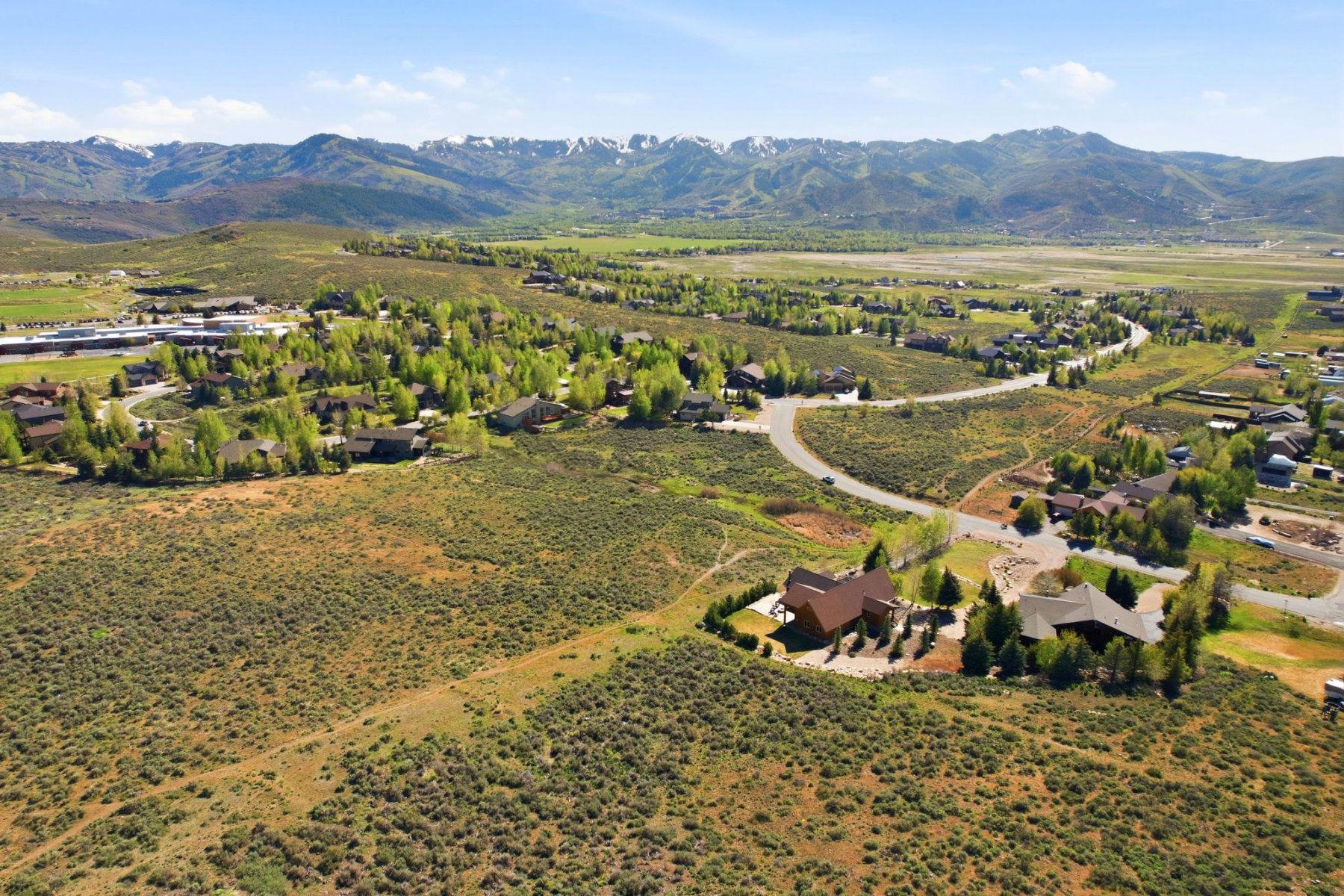 Expansive rural landscape featuring a mountainous backdrop, extensive natural shrubbery, and scattered residential properties