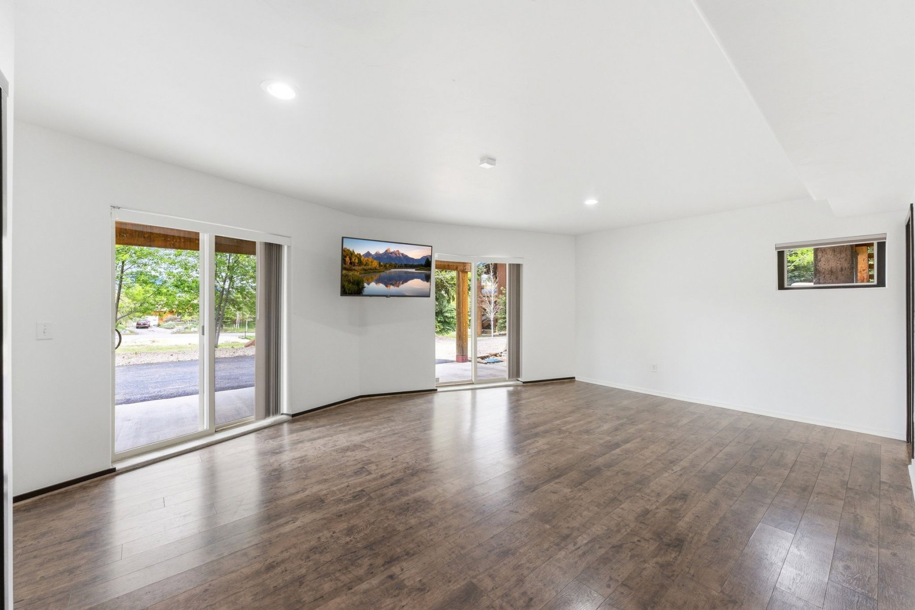 Spacious room featuring wood-finish flooring, white walls, and recessed lighting