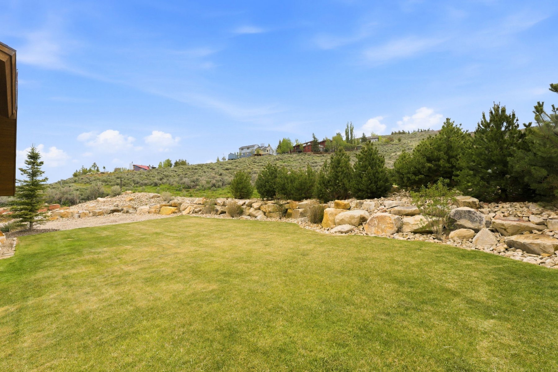 Expansive lawn area with a natural rock retaining wall