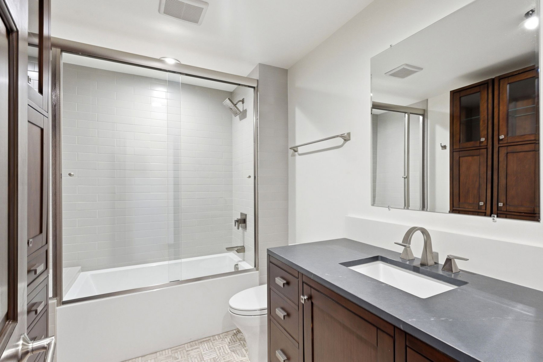 Bathroom featuring a dark wood-finish vanity with an integrated sink, a gray countertop, and brushed nickel fixtures
