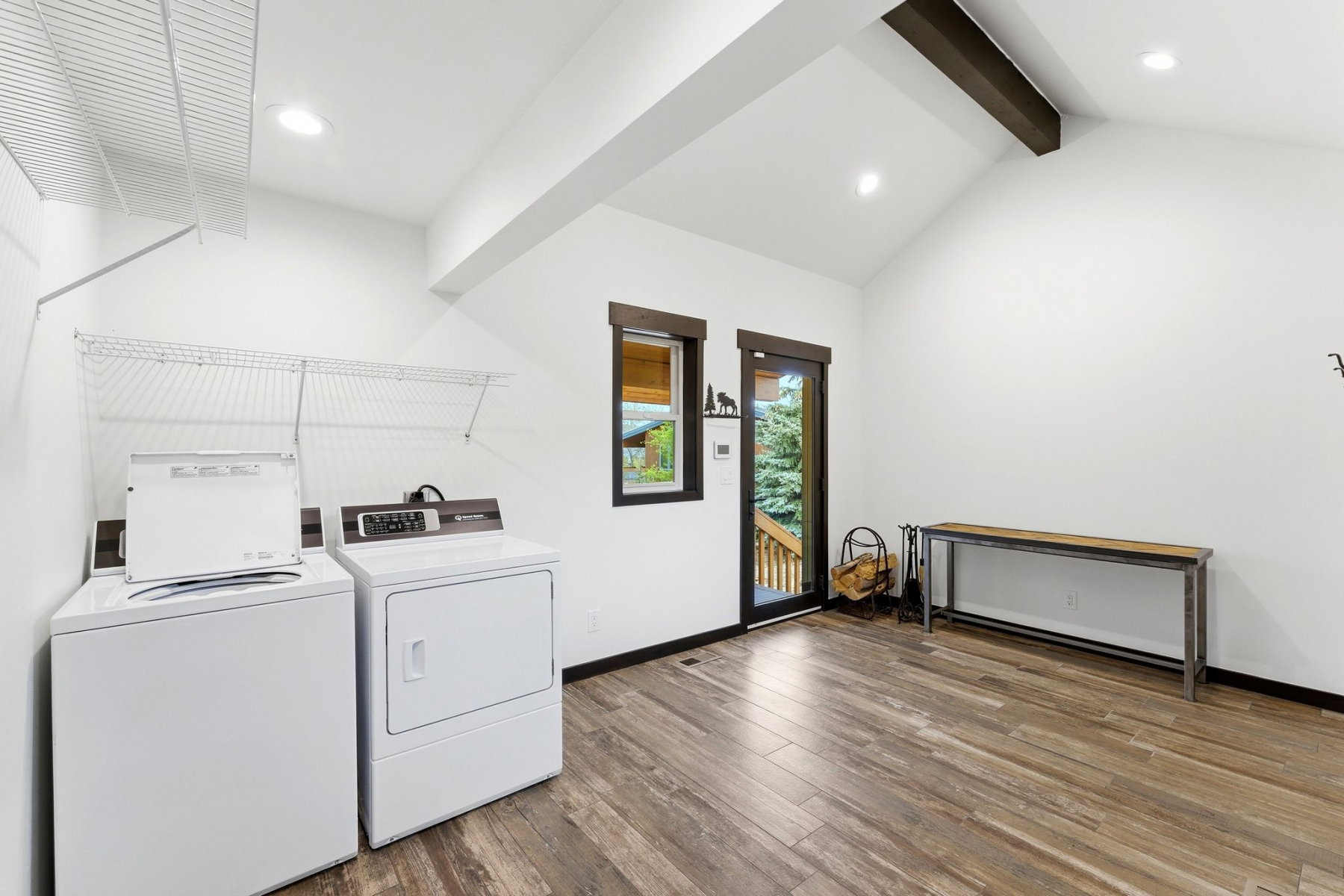 Spacious utility room featuring wood-finish flooring, vaulted ceilings with an exposed beam, recessed lighting, and ample shelving