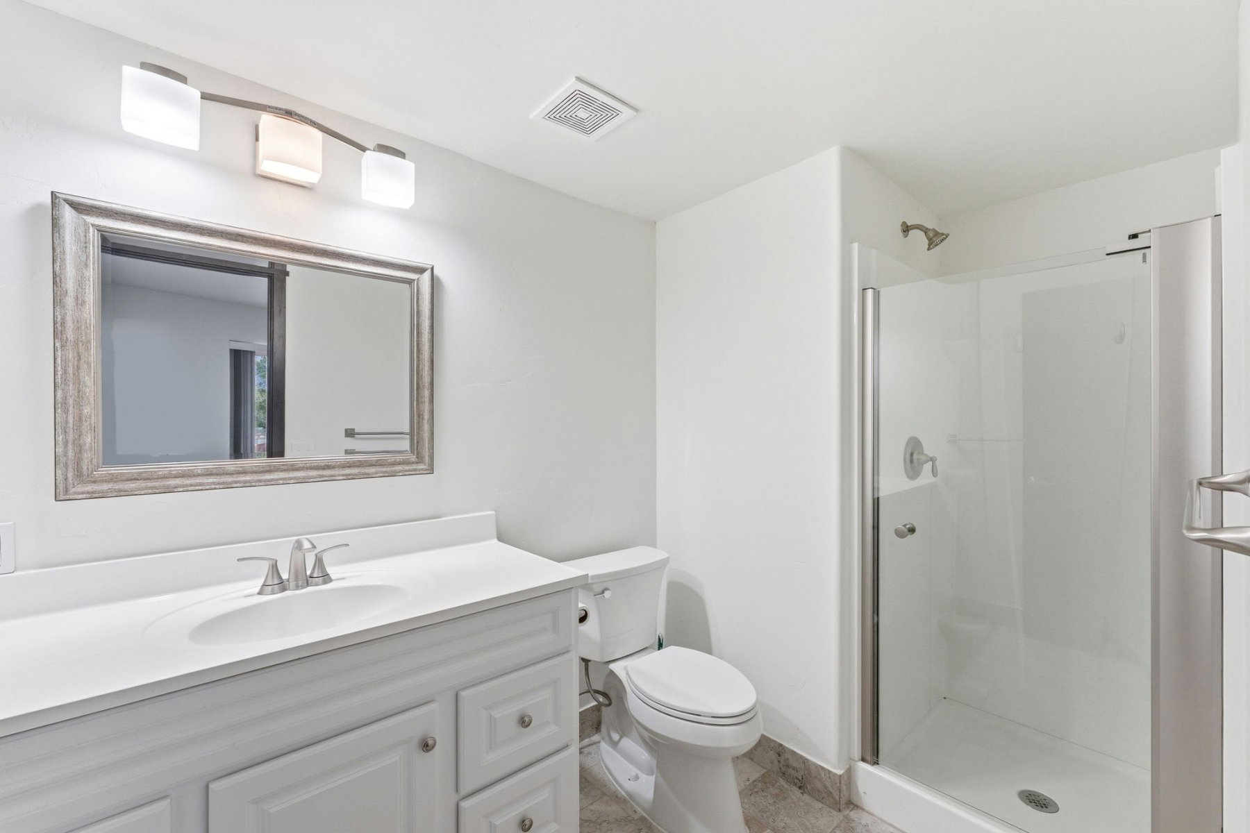 Bathroom featuring a white vanity with a single basin sink, framed mirror, and a three-light fixture