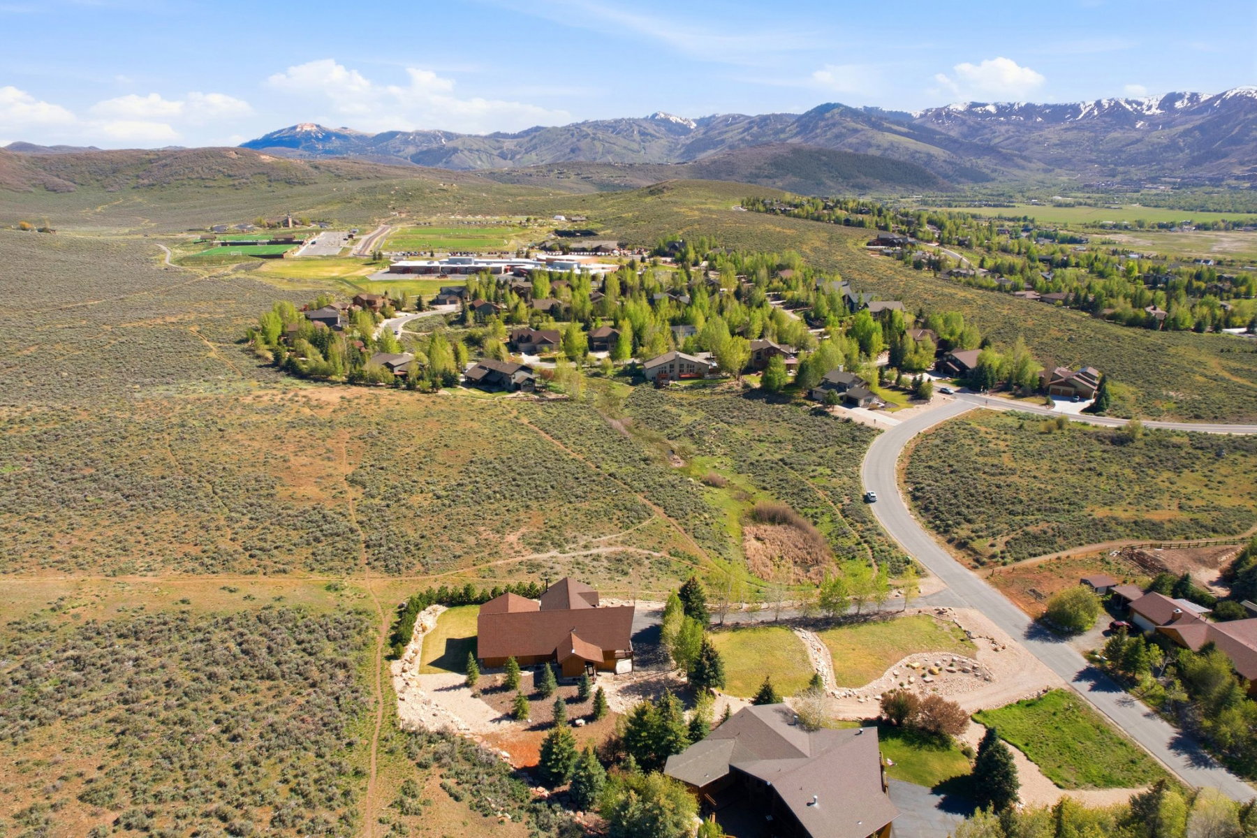Expansive mountain landscape featuring a winding road and a residential area with mature trees