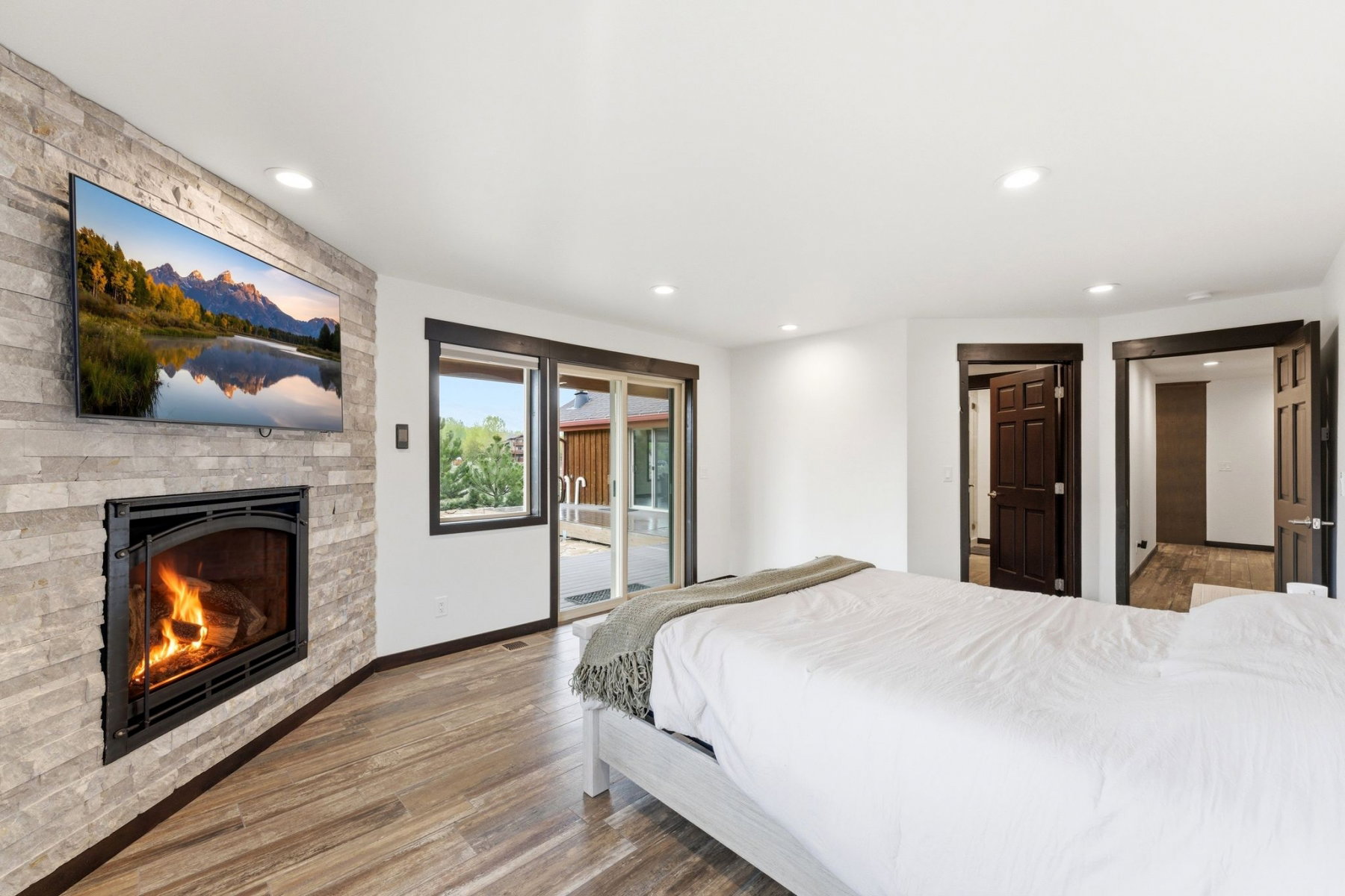 Interior room featuring a stone-clad fireplace, wood-finish flooring, recessed lighting, and a sliding glass door