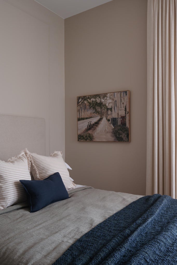 Warm-toned walls accenting a textile headboard, with full-height drapery panels providing natural light control