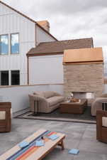 Rooftop patio with concrete flooring, a built-in stone fireplace, and a low privacy wall