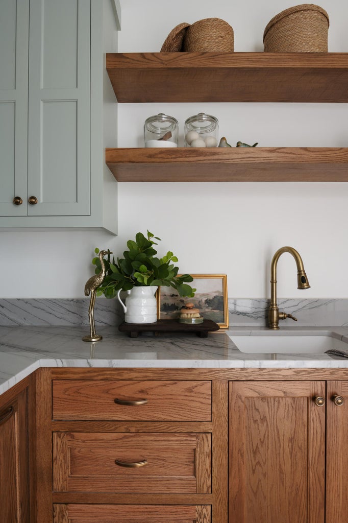 Kitchen or utility space featuring a white undermount sink with a brass-finish faucet