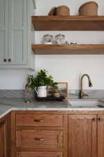 Kitchen or utility space featuring a white undermount sink with a brass-finish faucet
