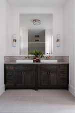 Dual vanity featuring dark wood cabinetry, light stone countertop, and two rectangular vessel sinks