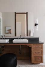 Double vanity with dark wood cabinetry, rectangular vessel sinks, and dark stone countertop