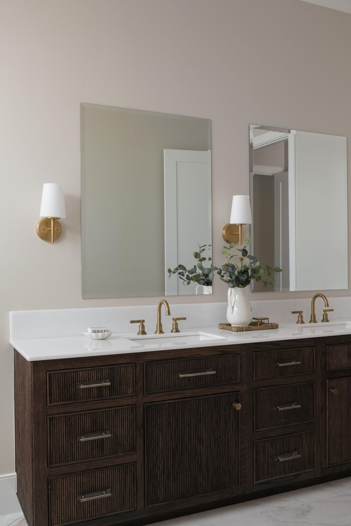 Double vanity featuring a white countertop with integrated sinks, brass-finish fixtures, and dark wood-finish cabinetry