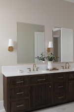 Double vanity featuring a white countertop with integrated sinks, brass-finish fixtures, and dark wood-finish cabinetry