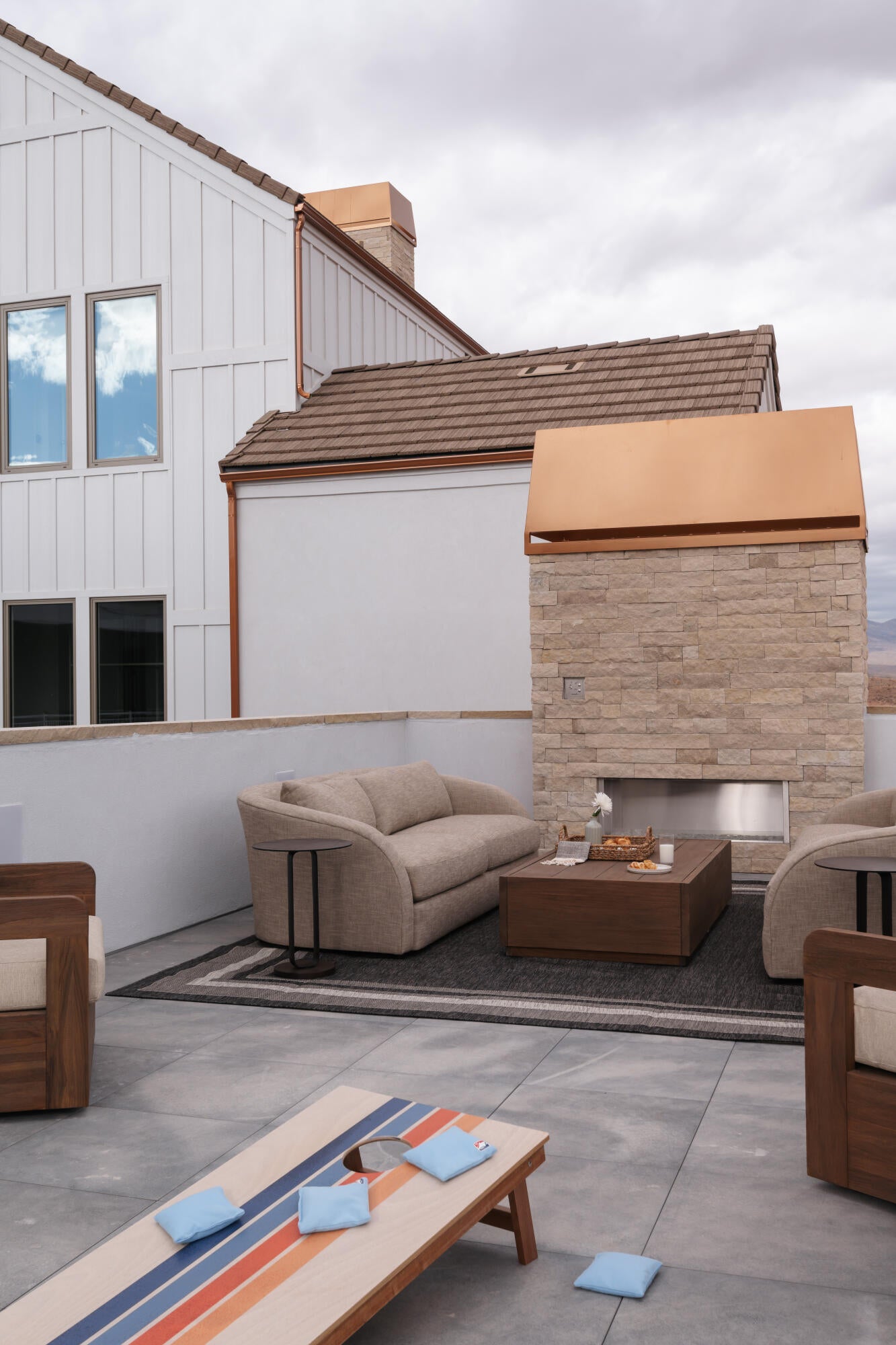 Rooftop patio featuring a stone-clad fireplace with a copper hood, concrete flooring, and a board and batten exterior