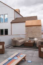 Rooftop patio featuring a stone-clad fireplace with a copper hood, concrete flooring, and a board and batten exterior