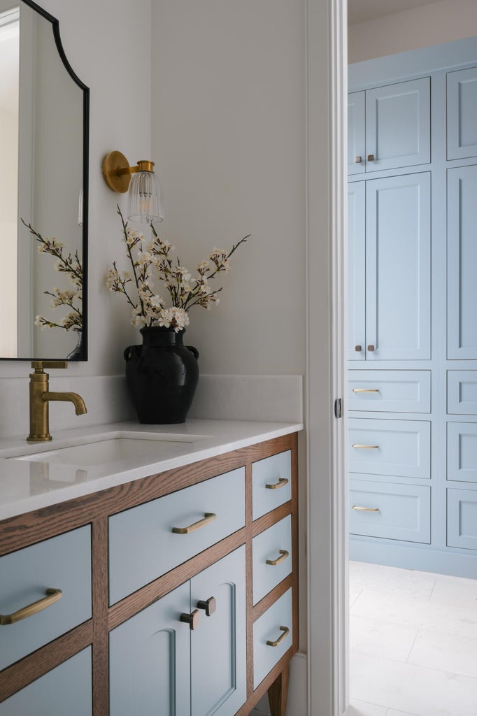 Custom vanity featuring wood-finish framing and light blue cabinet fronts with brass hardware